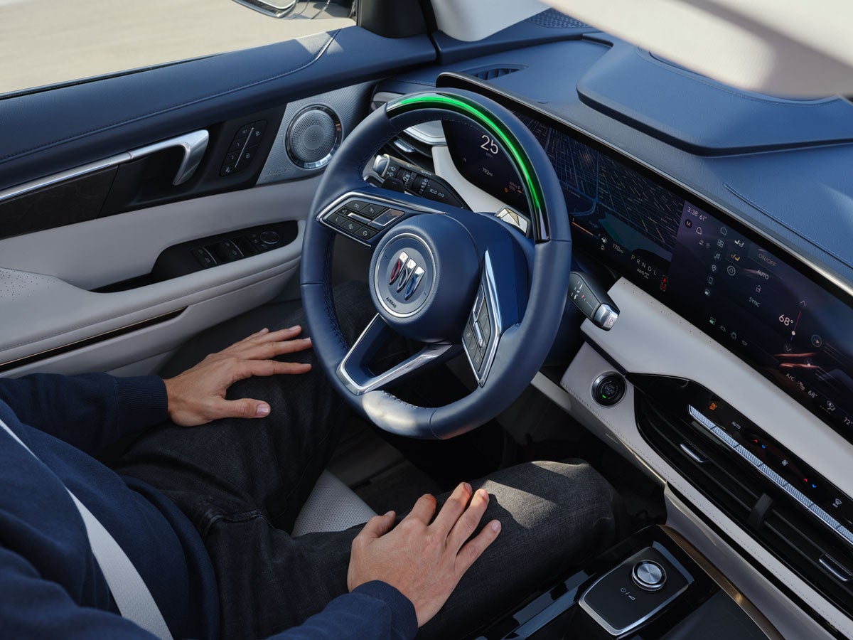 Driver's perspective of a modern Buick interior with a digital dashboard and driver-assist steering wheel.